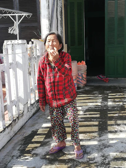 A friendly caregiver assisting an elderly person outside a cozy home on a sunny day.