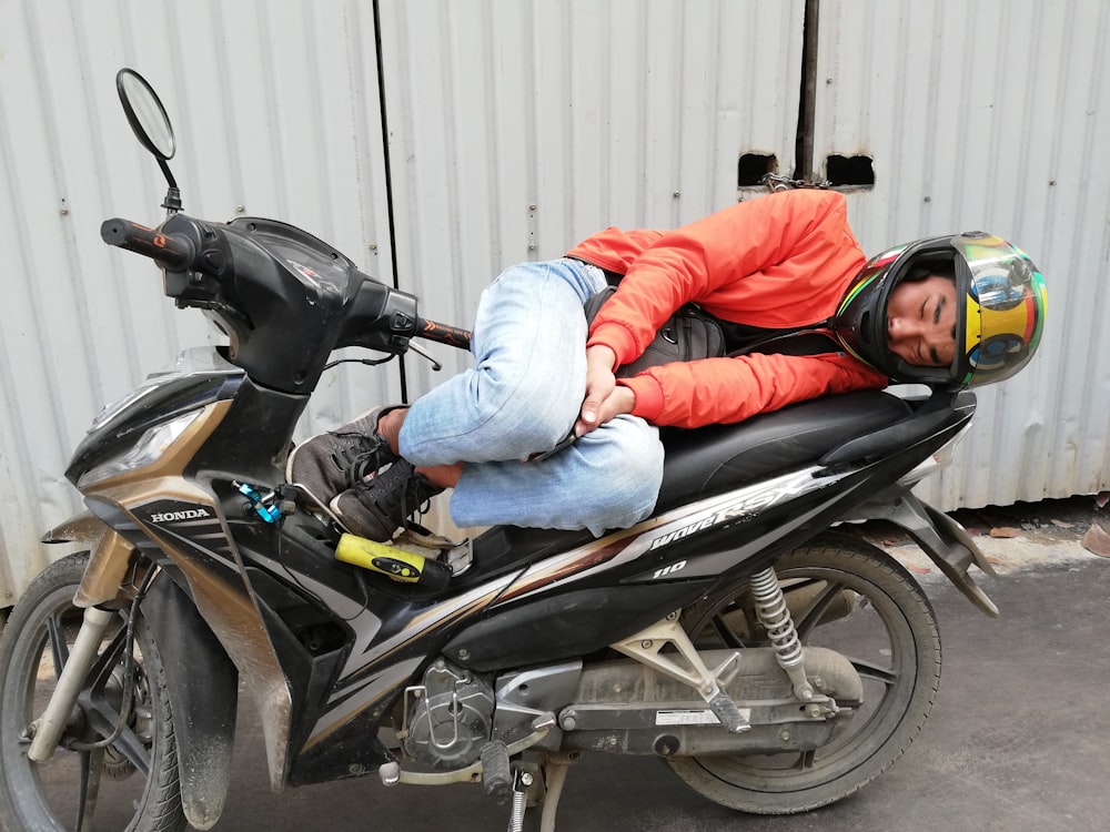 man in red jacket and blue denim jeans sitting on black motorcycle