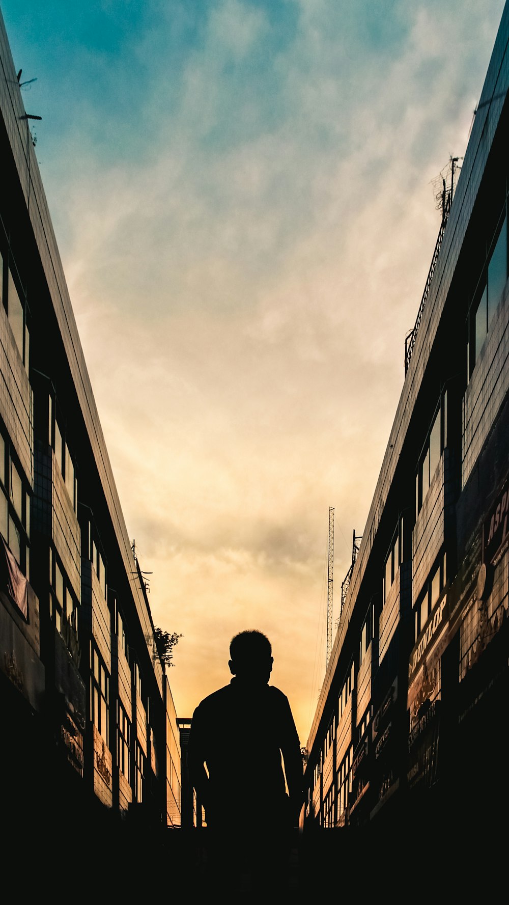homem em jaqueta preta em pé entre os edifícios durante o dia