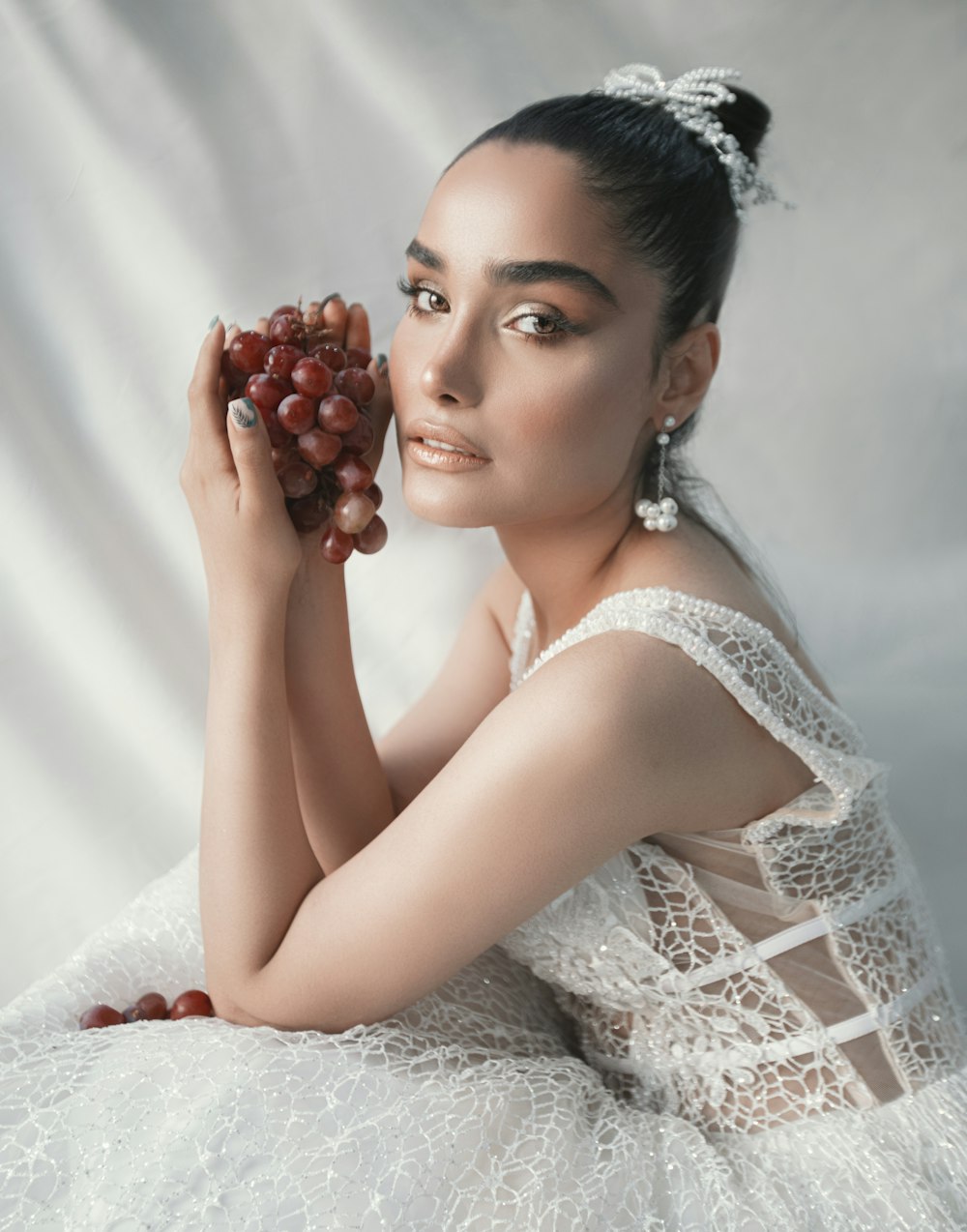 woman in white lace dress holding red round fruit