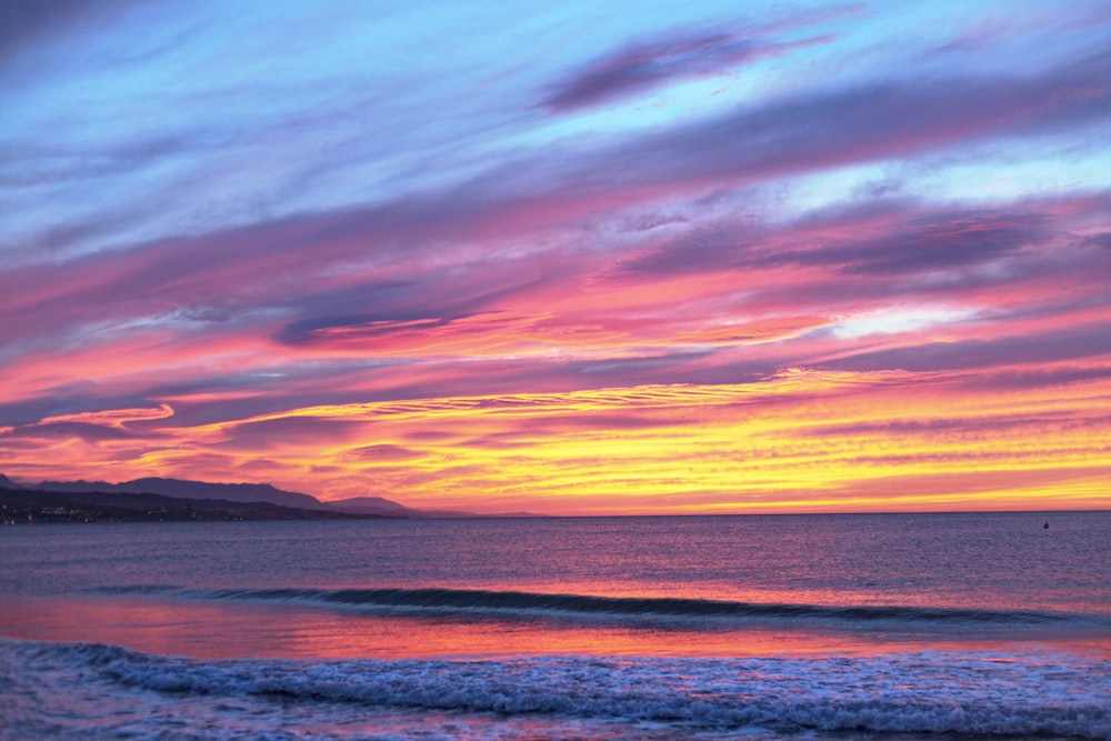 Cuerpo de agua bajo cielo nublado durante la puesta del sol