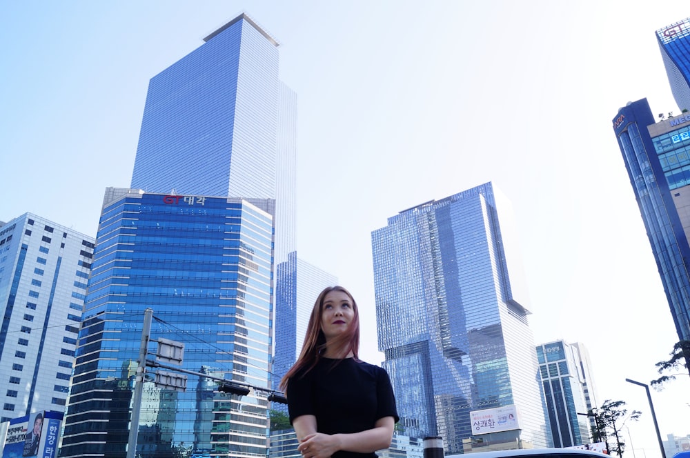 woman in black shirt standing near high rise buildings during daytime