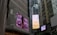 Tall urban buildings with large digital billboards displaying advertisements. One billboard shows a close-up of a face with an expressive emotion, and another displays a clock advertisement.