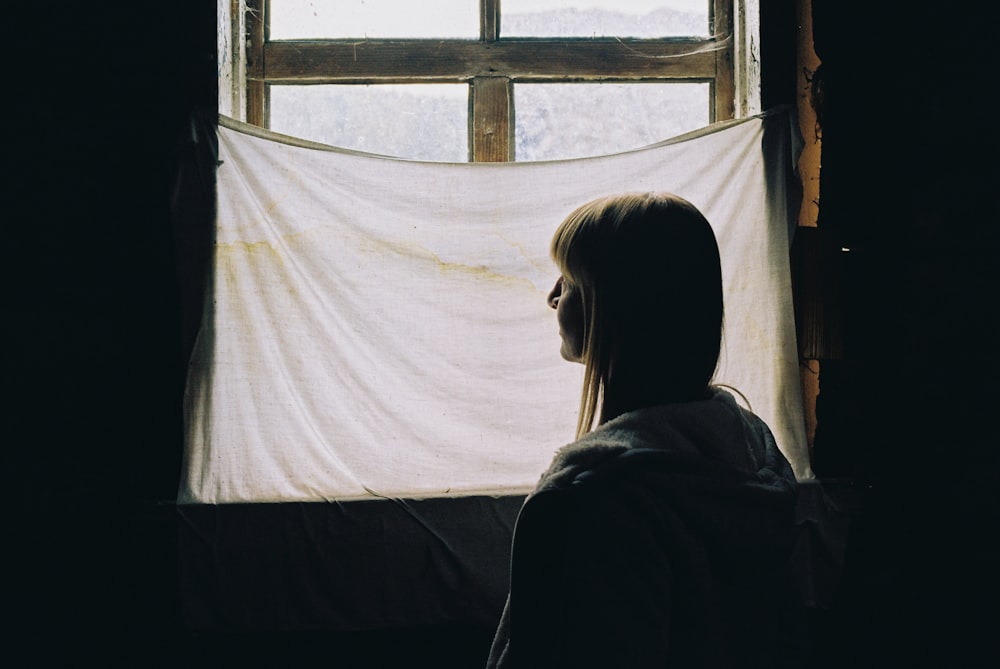 woman in black shirt standing in front of window