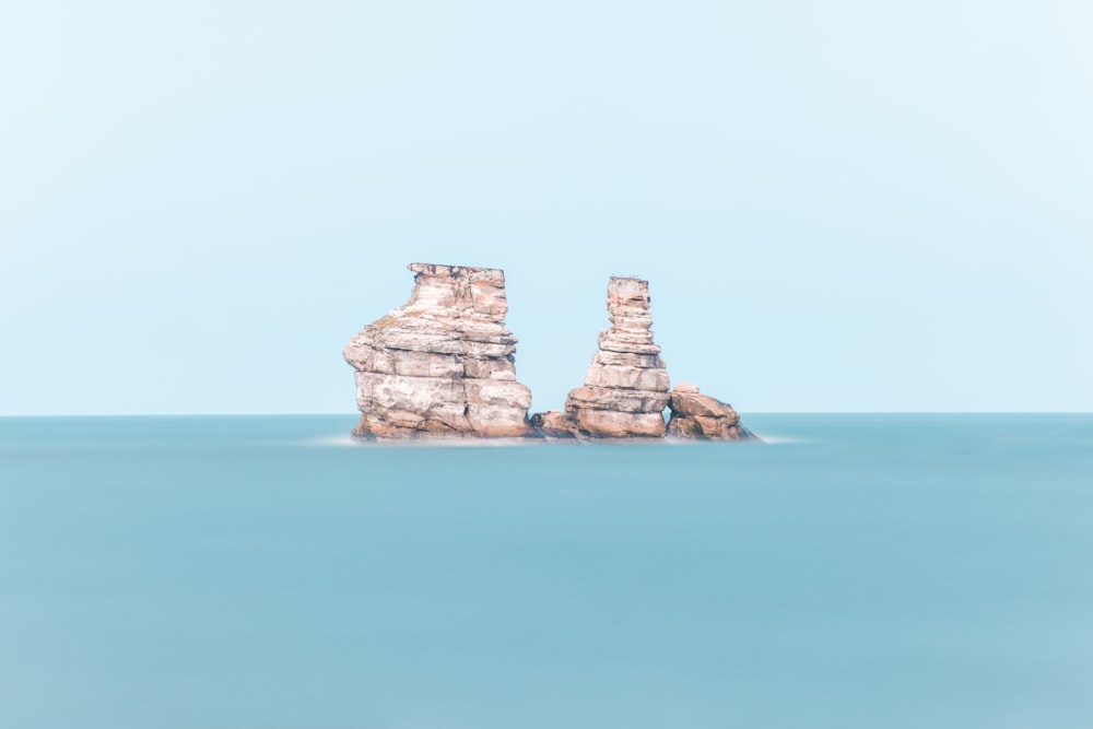 brown rock formation on blue sea under blue sky during daytime