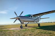 blue and white airplane on green grass field under blue sky during daytime