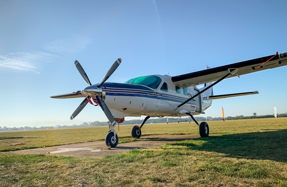 blue and white airplane on green grass field under blue sky during daytime