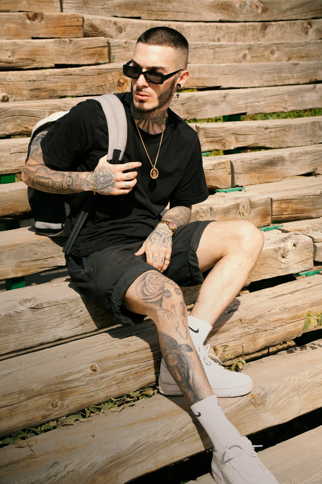 man in black jacket sitting on brown wooden bench