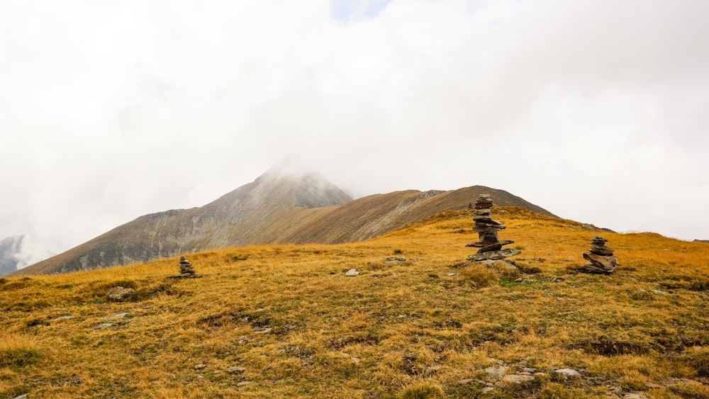 green grass field near mountain under white clouds during daytime