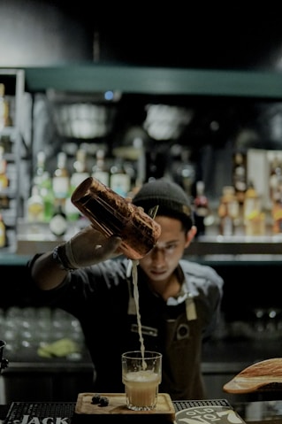 man in black and white polo shirt holding brown glass bottle