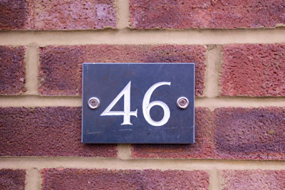 Close-up of a slate address plaque with elegant engraving nestled among lush greenery.