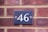 Close-up of a sleek laser-cut steel house number plate mounted on a garden wall.