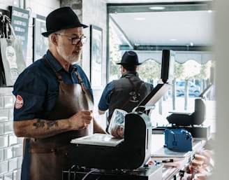 man in blue vest and black apron cooking