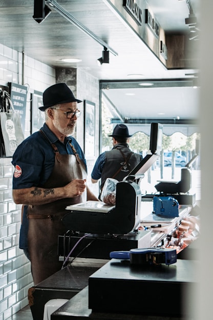 man in blue vest and black apron cooking