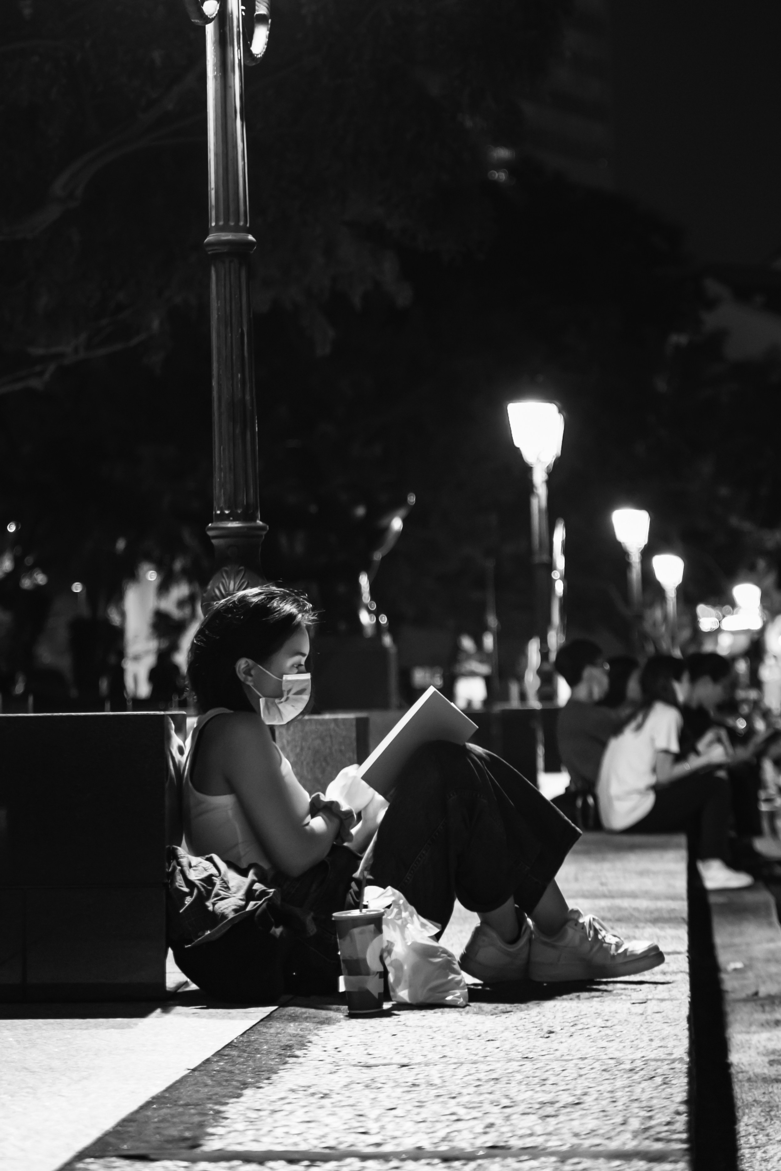 草原に座っているチューブドレスの女性のグレースケール写真