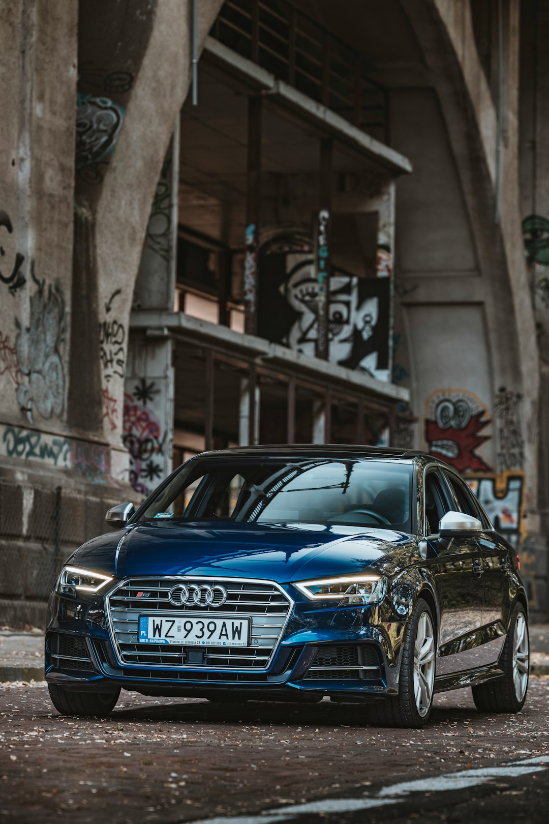 blue audi a 4 sedan parked beside gray concrete building during daytime