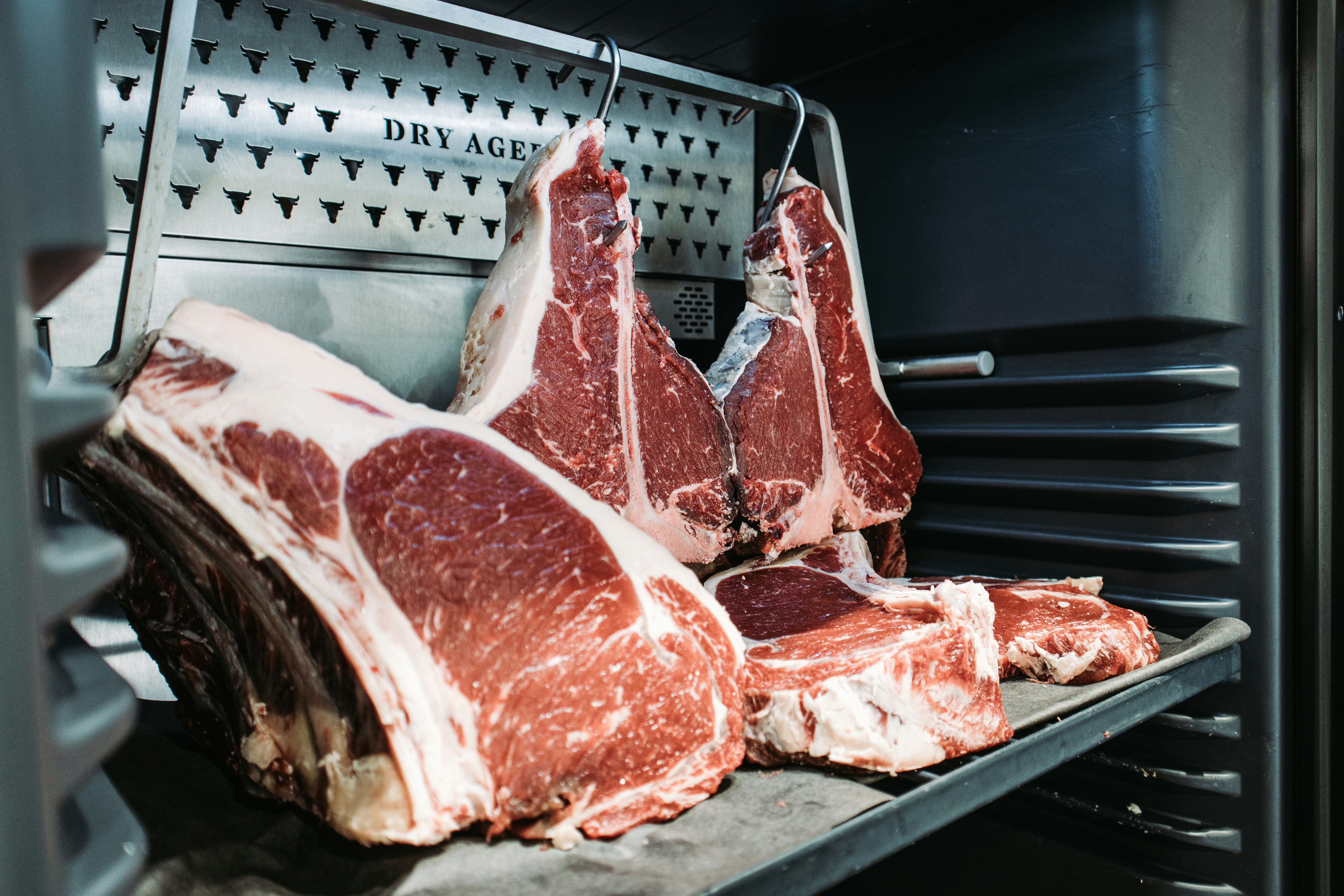 Dry-aged beef hanging in dark cold storage, deep mahogany crust, aged patina