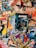 A collection of various comic books scattered on a surface. The comic books feature popular superheroes like Batman and Superman. The covers display colorful, dynamic illustrations with bold titles and iconic characters in action poses.