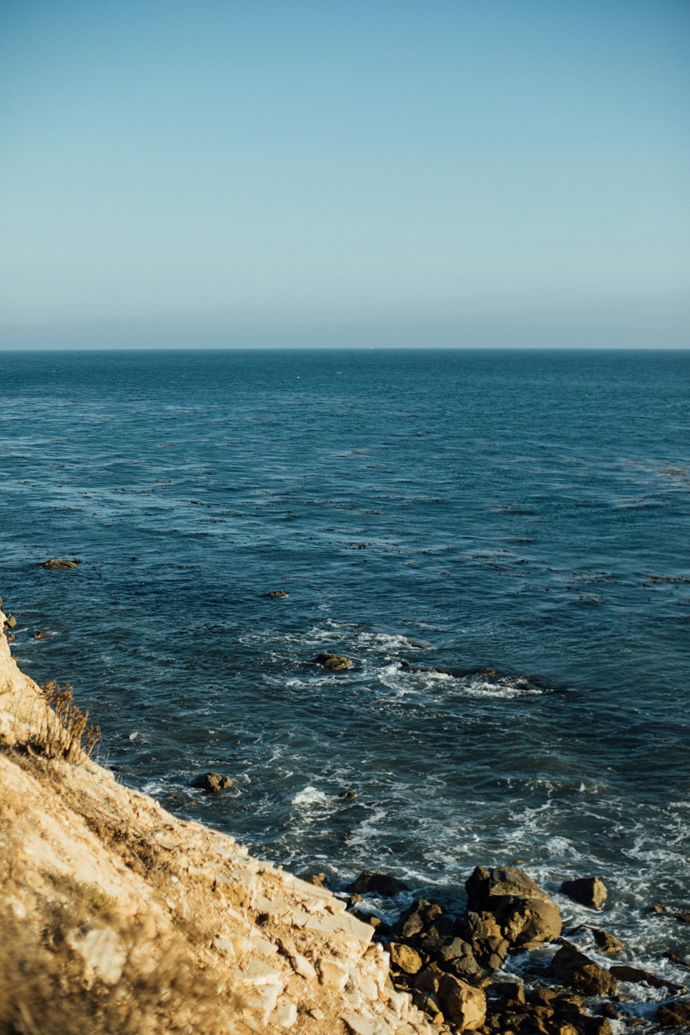 brown rocky mountain beside blue sea during daytime