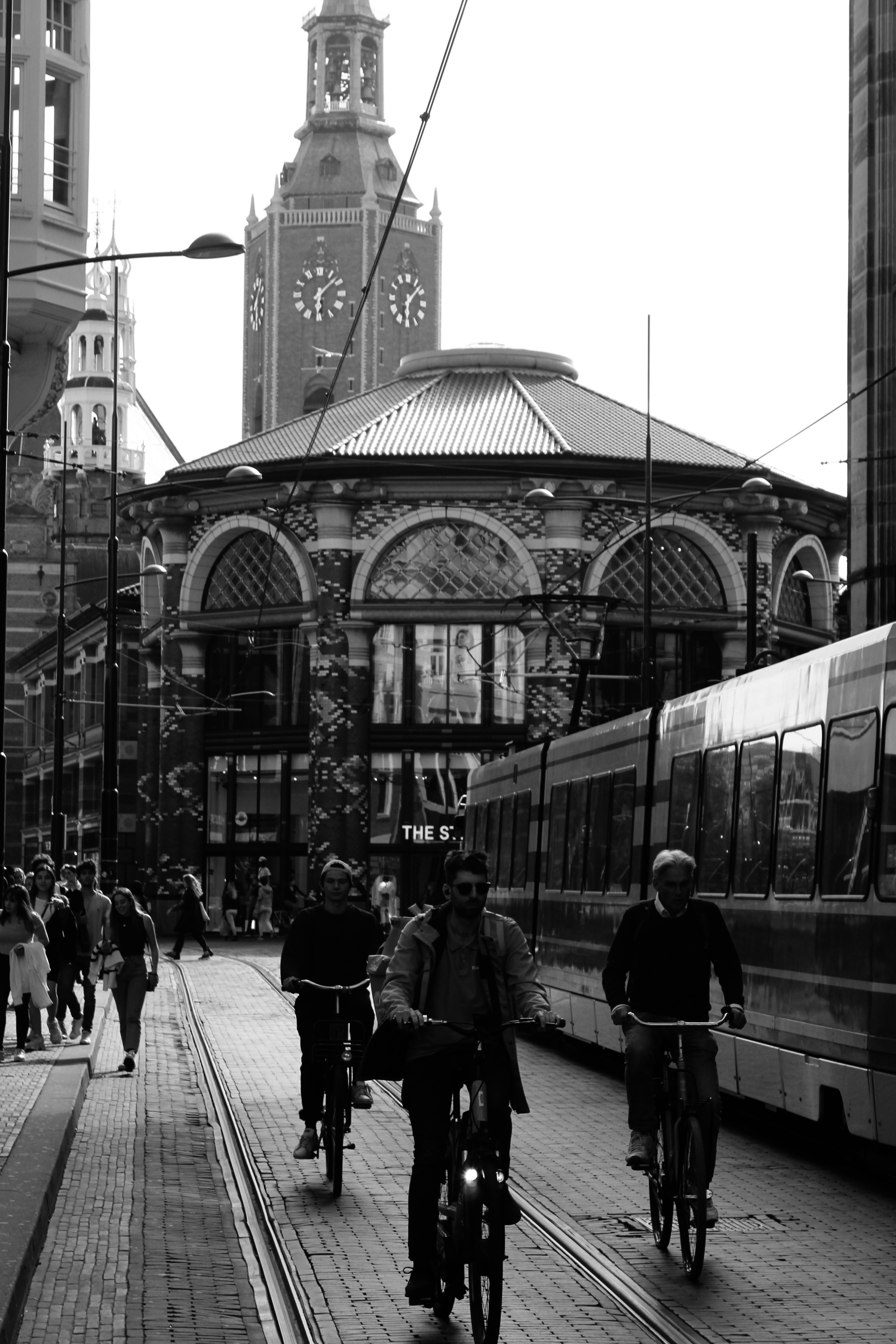 Photo en niveaux de gris de personnes marchant sur le trottoir près de la gare