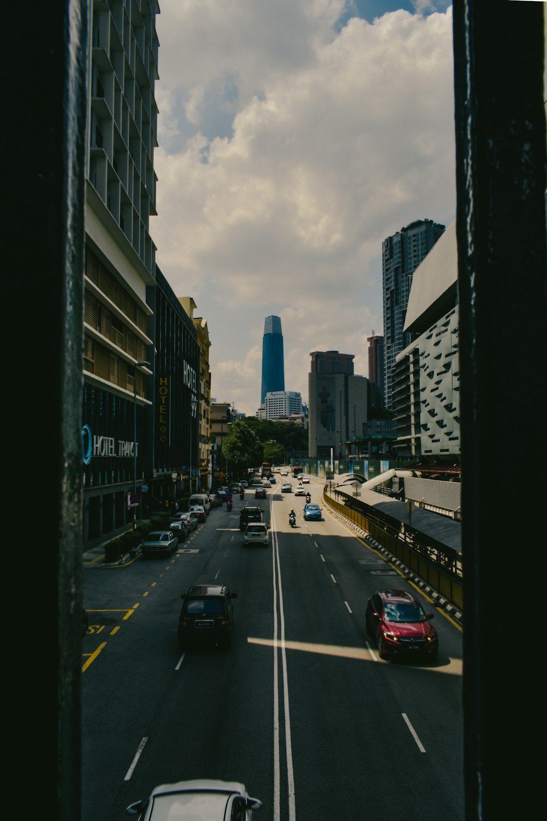 cars on road between high rise buildings during daytime