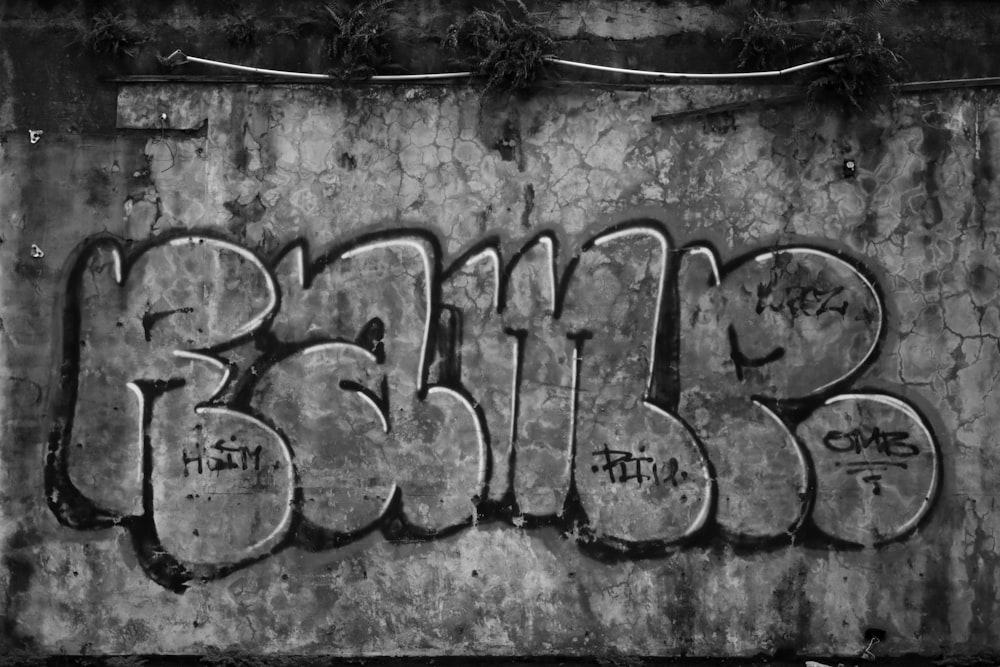 grayscale photo of concrete wall with graffiti