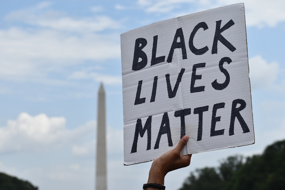 person holding white and black welcome to the beach signage