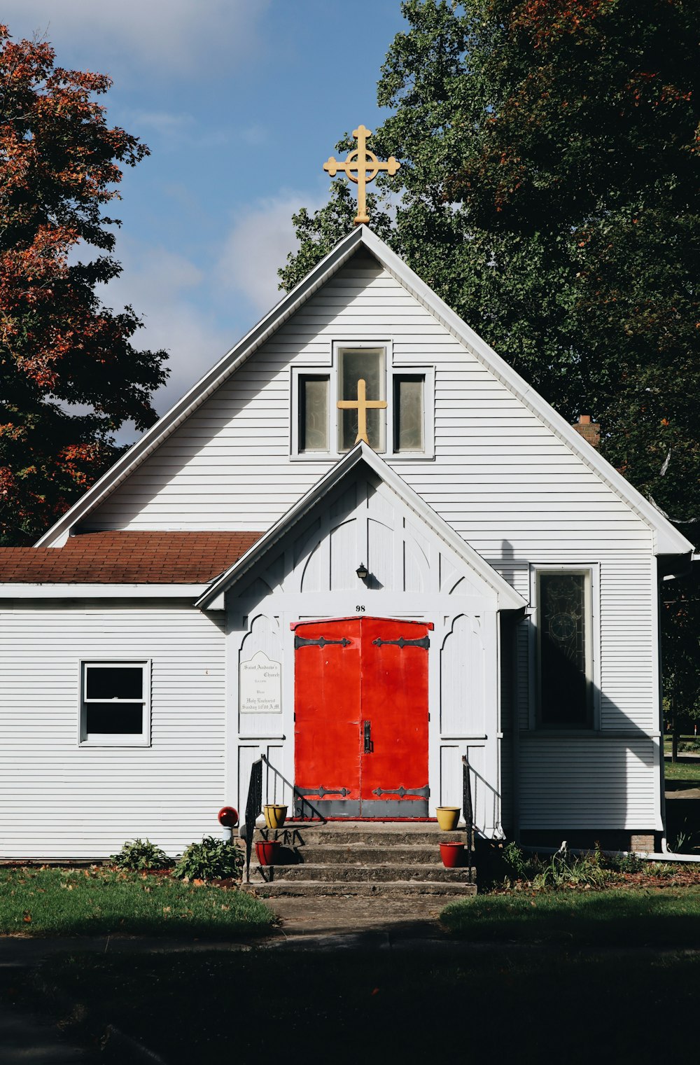 white and red wooden house near green trees under blue sky during daytime