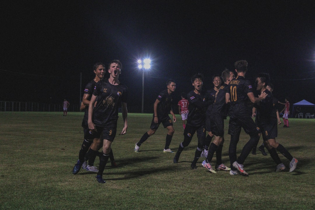 group of men in black uniform standing on green grass field during nighttime