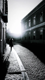 woman in black coat walking on street during daytime
