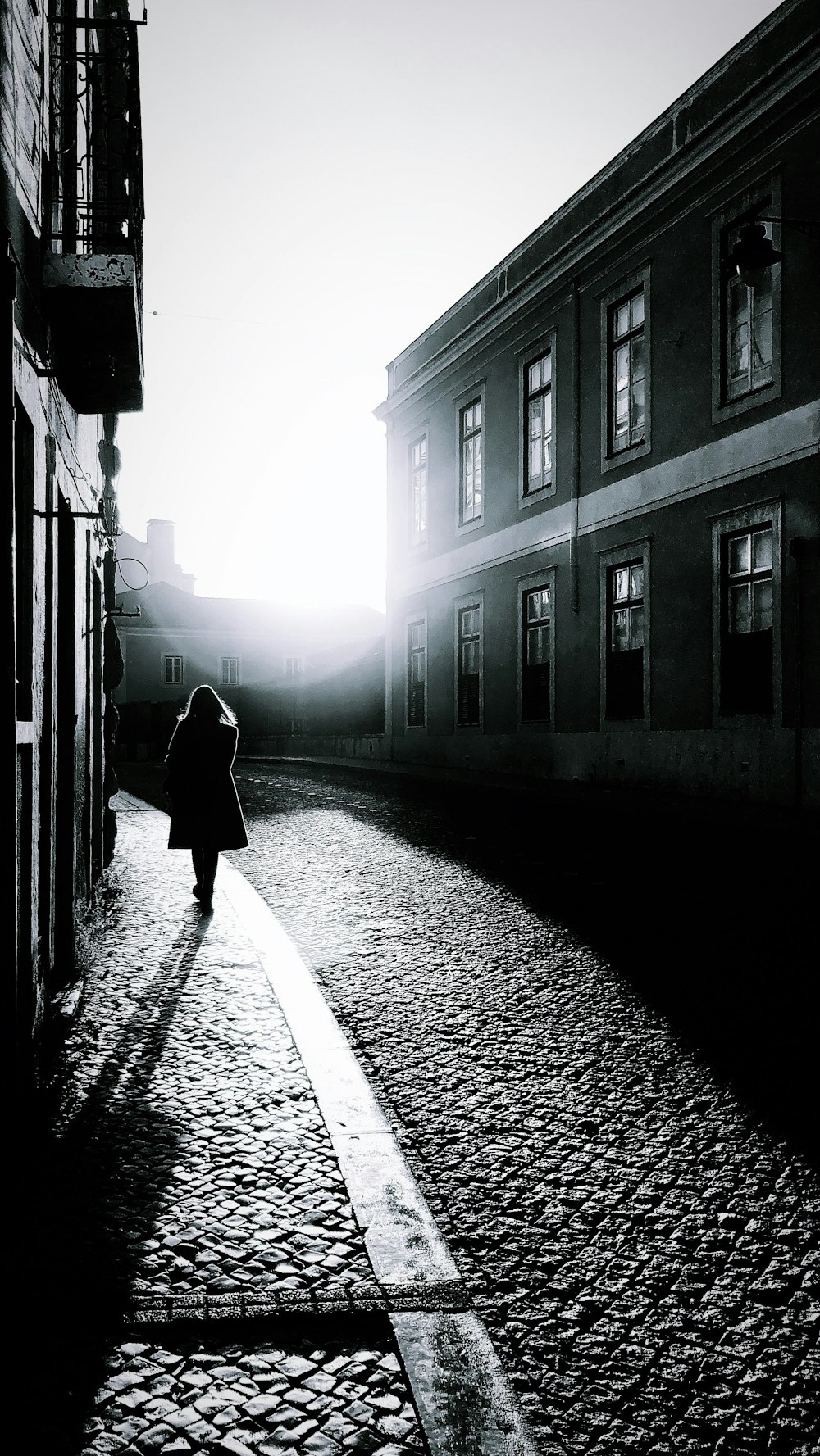 woman in black coat walking on street during daytime