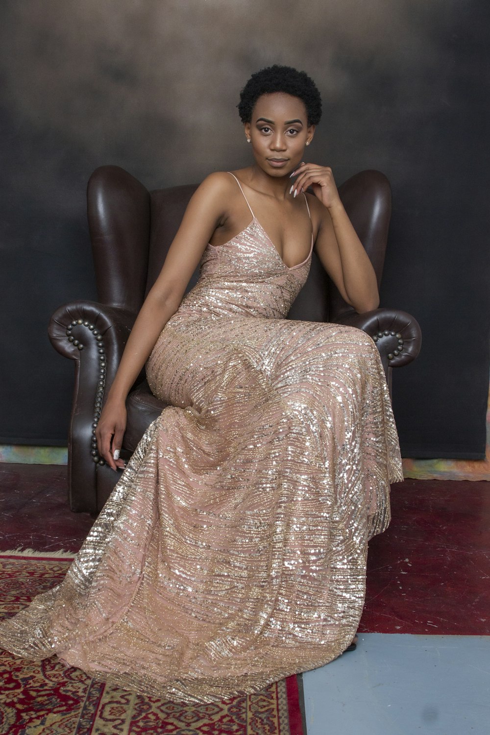 woman in brown floral dress sitting on black leather armchair