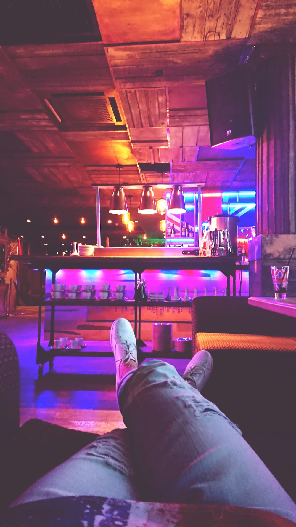 person in blue denim jeans and white sneakers sitting on chair