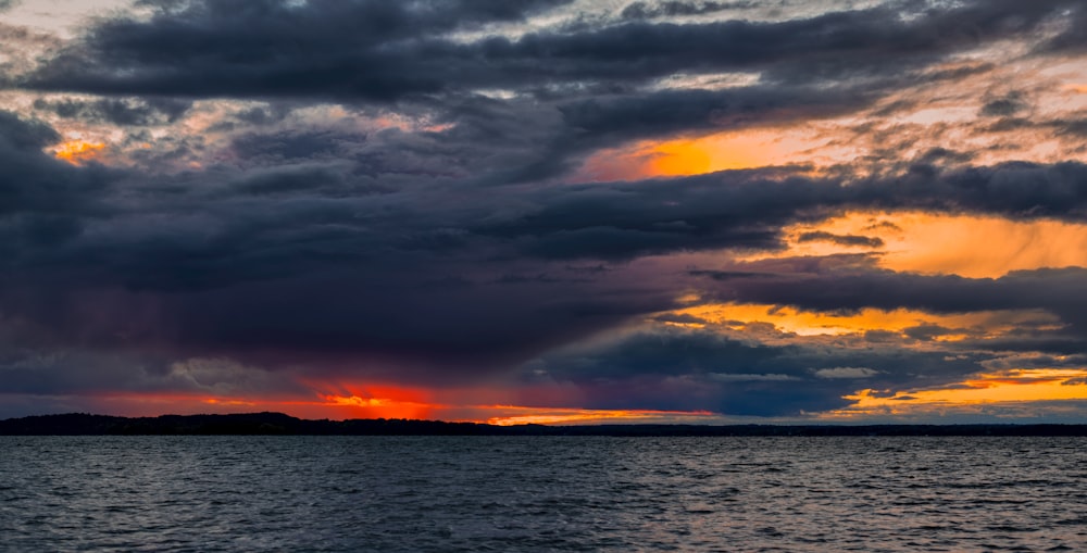 body of water under cloudy sky during sunset