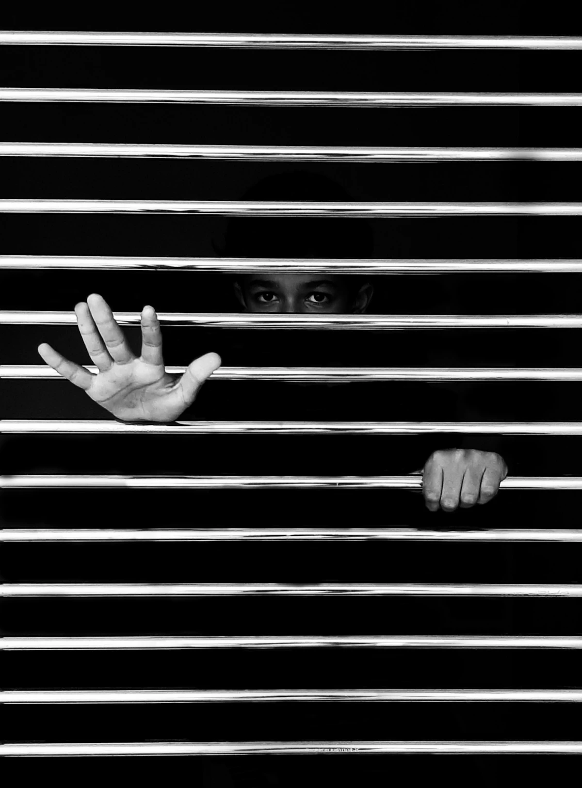 A hand reaching through black metal railing