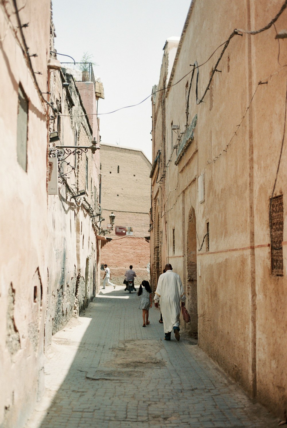 man in white thobe walking on sidewalk during daytime