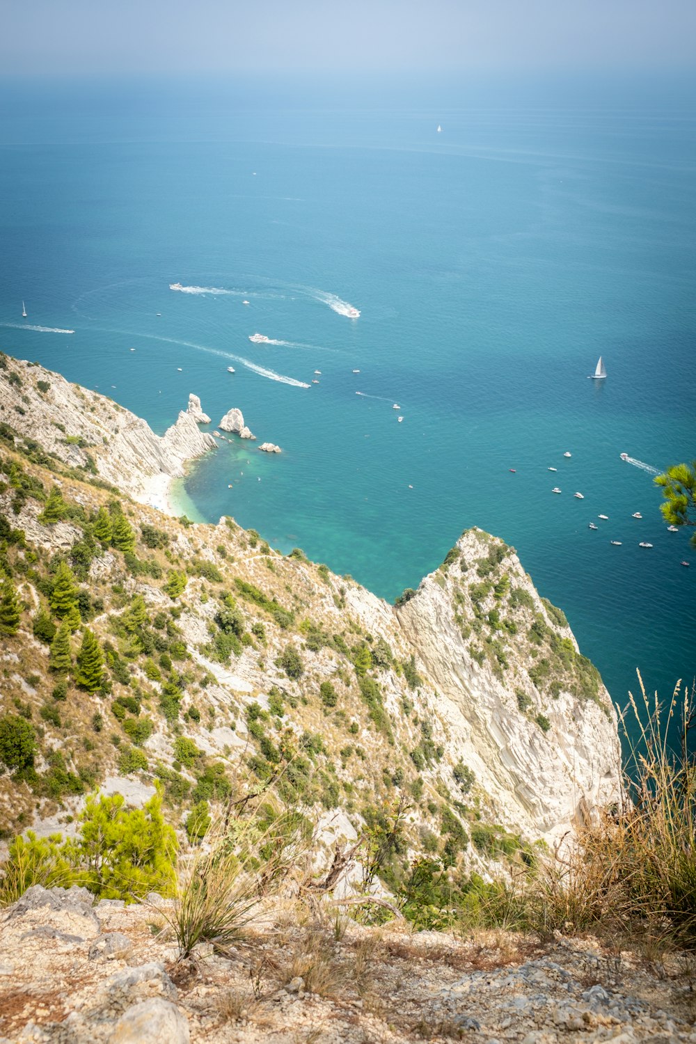 Vue aérienne de la montagne verte et grise au bord de la mer bleue pendant la journée