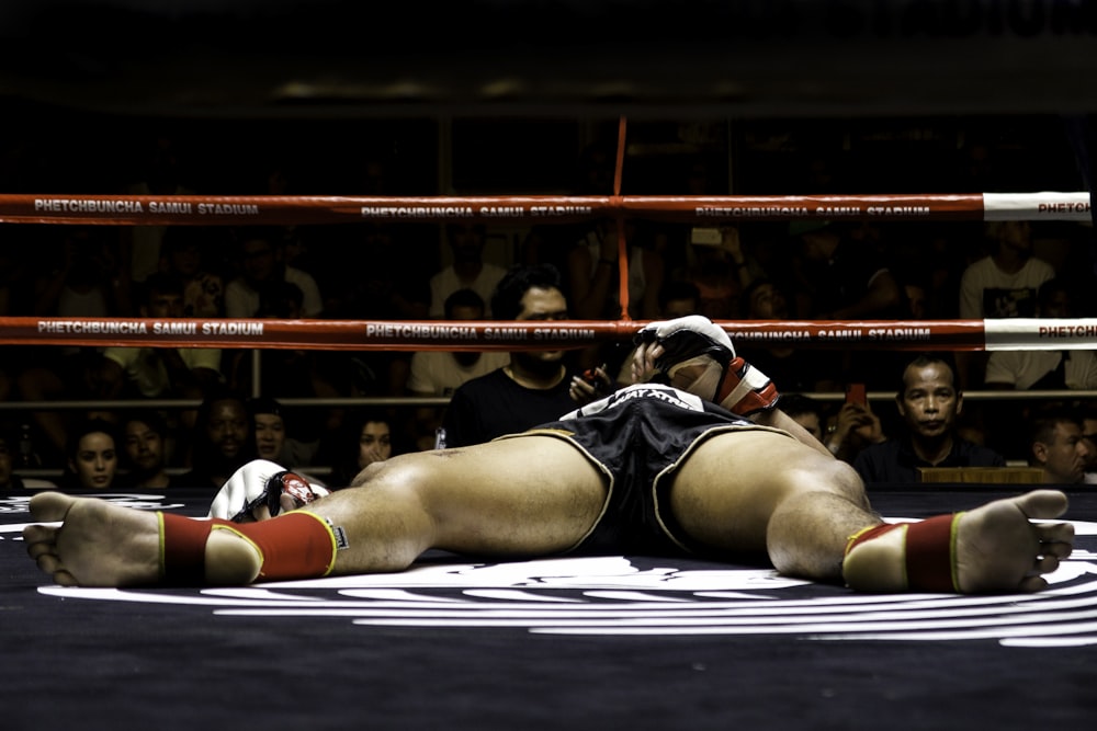 woman in black and white sports bra and black shorts lying on floor