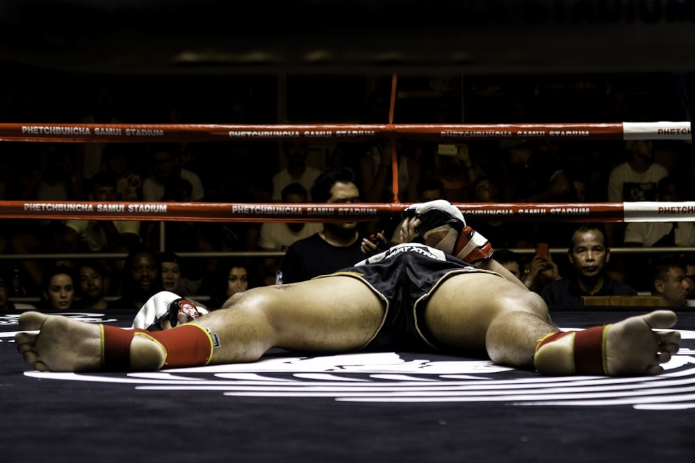 femme en soutien-gorge de sport noir et blanc et short noir allongé sur le sol