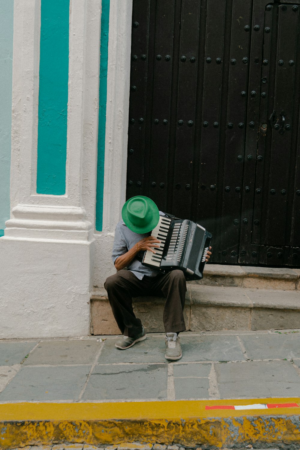 man in black jacket and brown pants sitting on white concrete bench