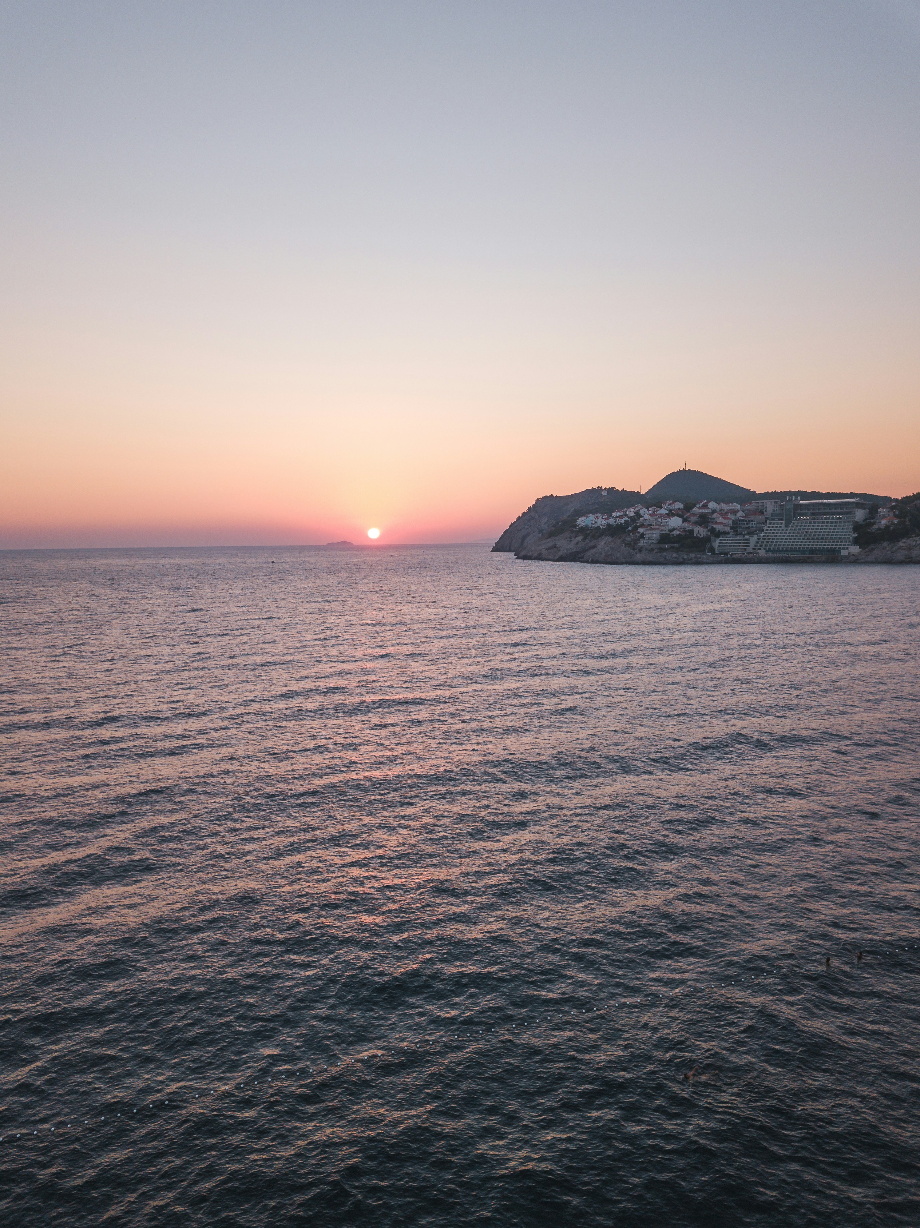 silhouette of mountain beside sea during sunset