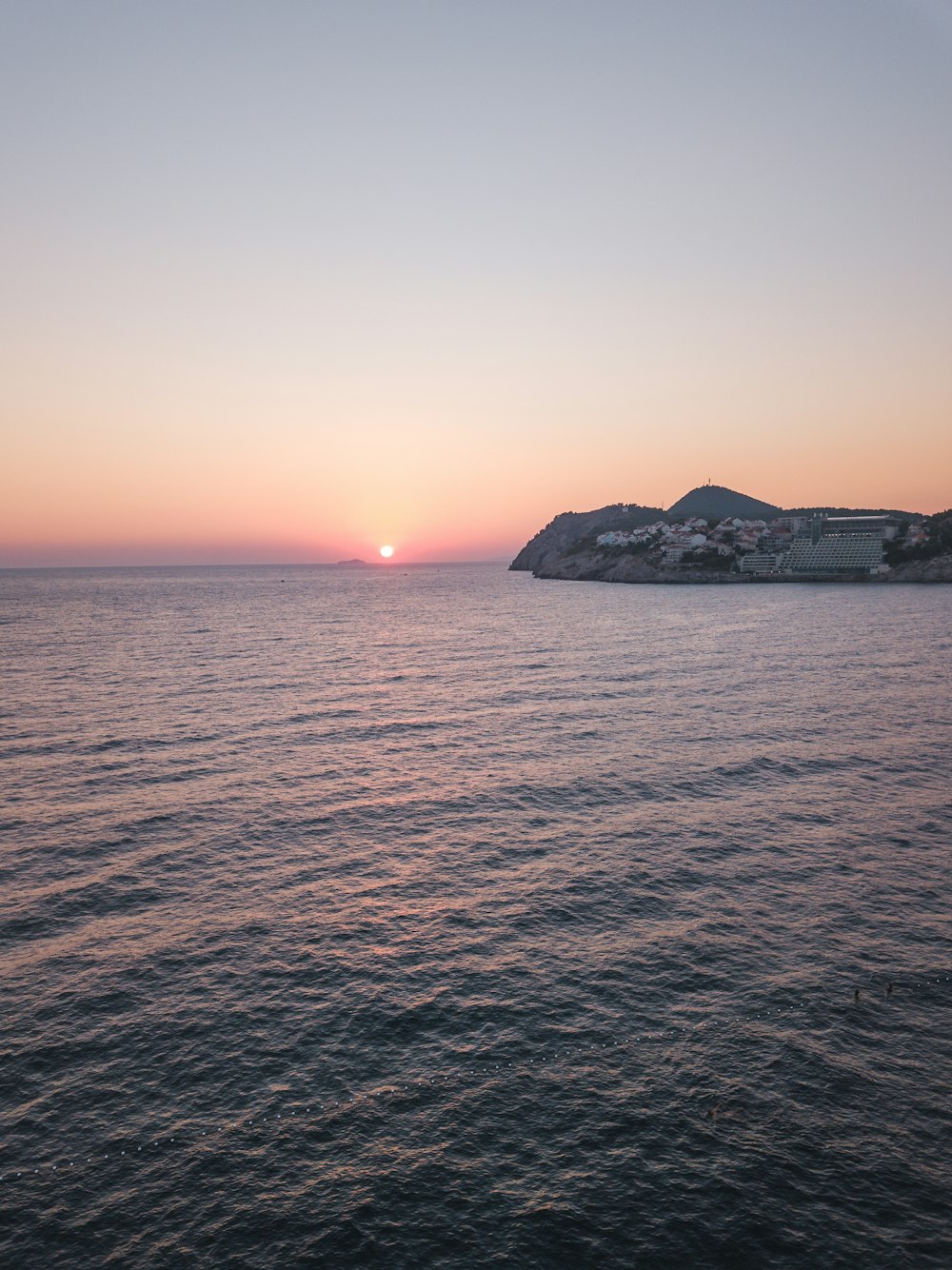 silhouette of mountain beside sea during sunset