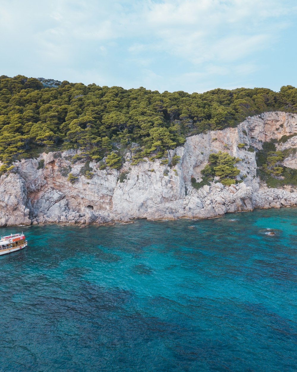 white boat on sea near green and brown mountain during daytime