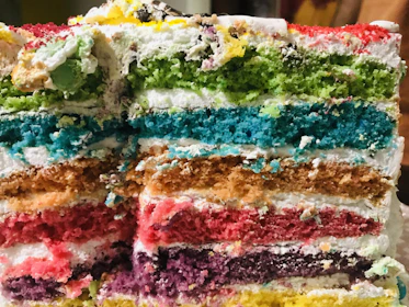 Close-up of a beautifully frosted layered cake with pastel decorations.