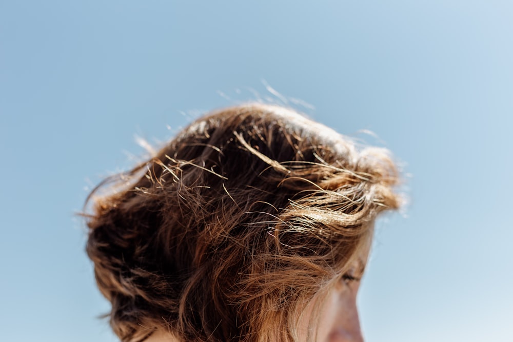 mulher com cabelo castanho sob o céu azul durante o dia