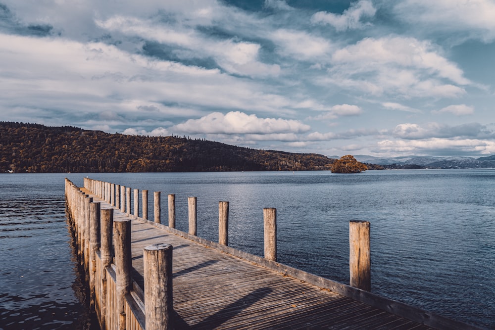 brown wooden dock on blue sea under white clouds during daytime