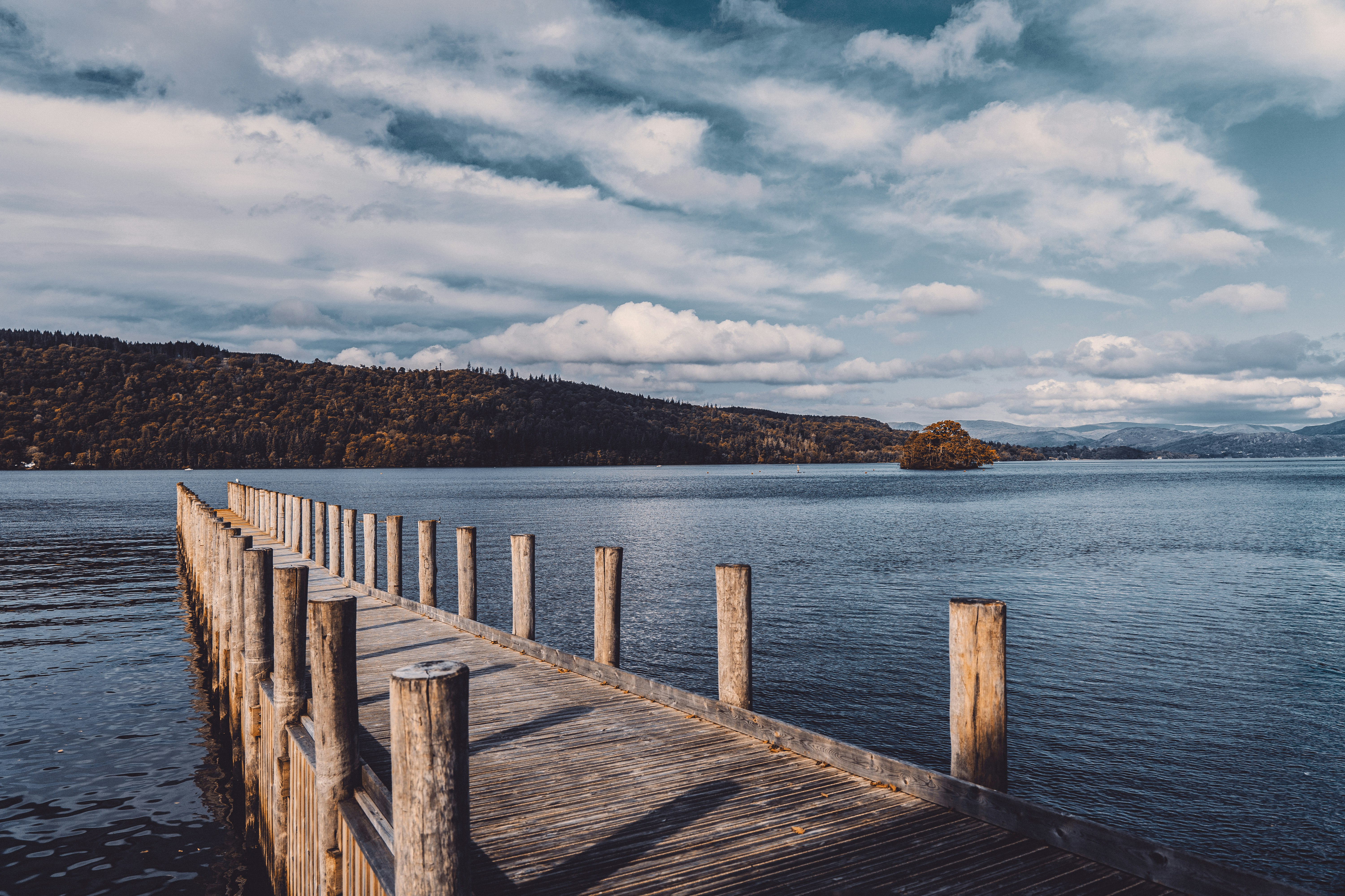 brown wooden dock on blue sea under white clouds during daytime