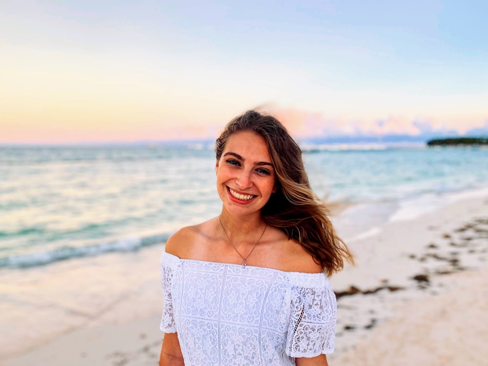 woman in white off shoulder dress standing on beach during daytime