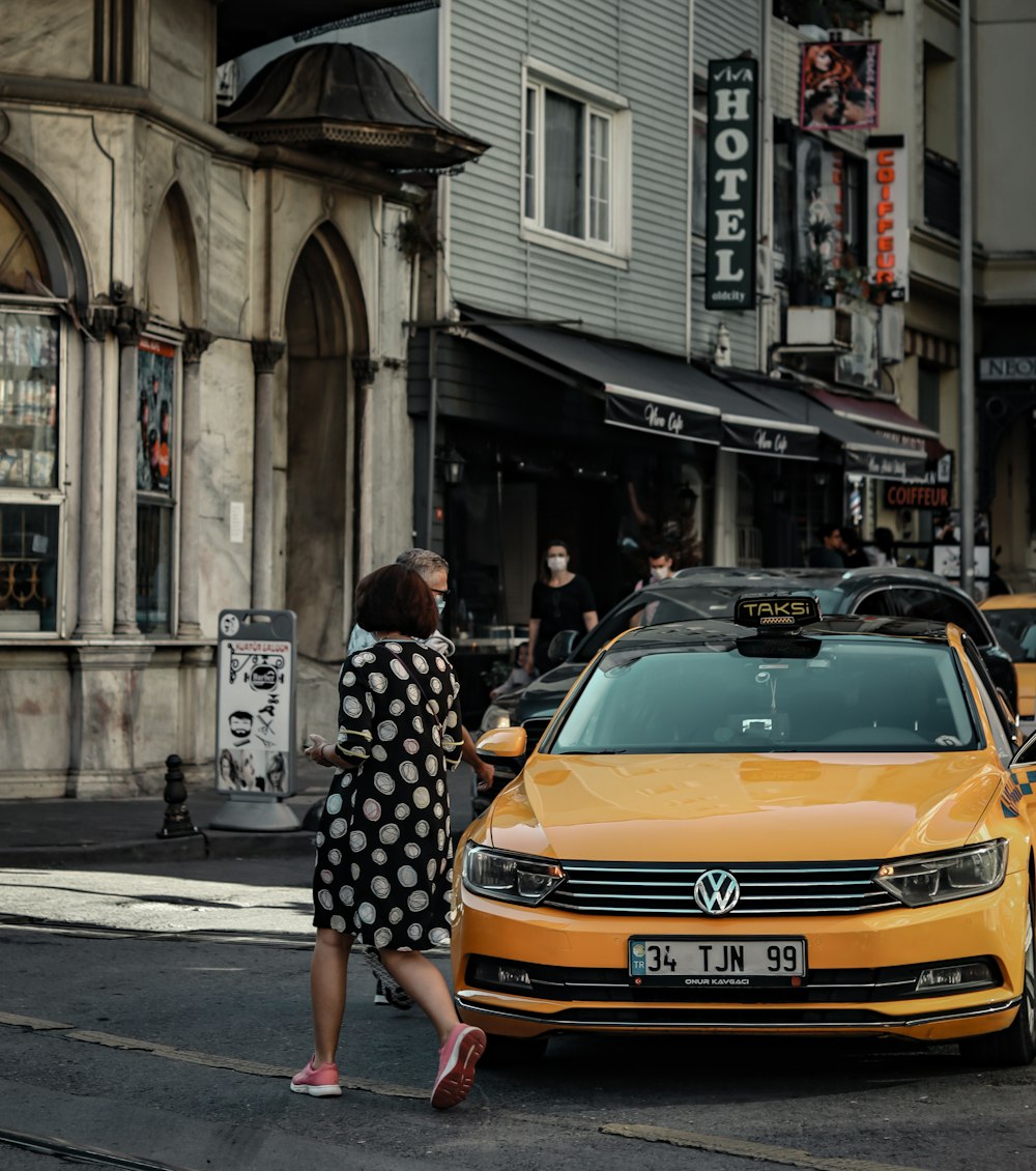 femme en robe à fleurs noire et blanche marchant sur le trottoir pendant la journée