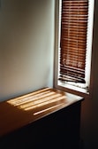 Close-up of wooden Venetian blinds filtering warm sunlight into a cozy home.